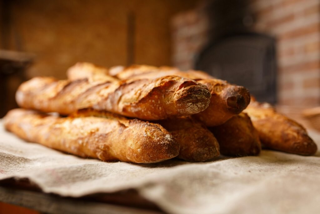 Warm, freshly baked rustic baguettes stacked in a cozy bakery setting.